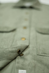 Close-up of a green corduroy shirt with buttons and a pocket.