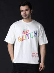 A male model wearing a white oversized T-shirt with a colorful text and graphic print on the front and back.