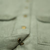 Close-up of a green corduroy shirt with buttons and a pocket.